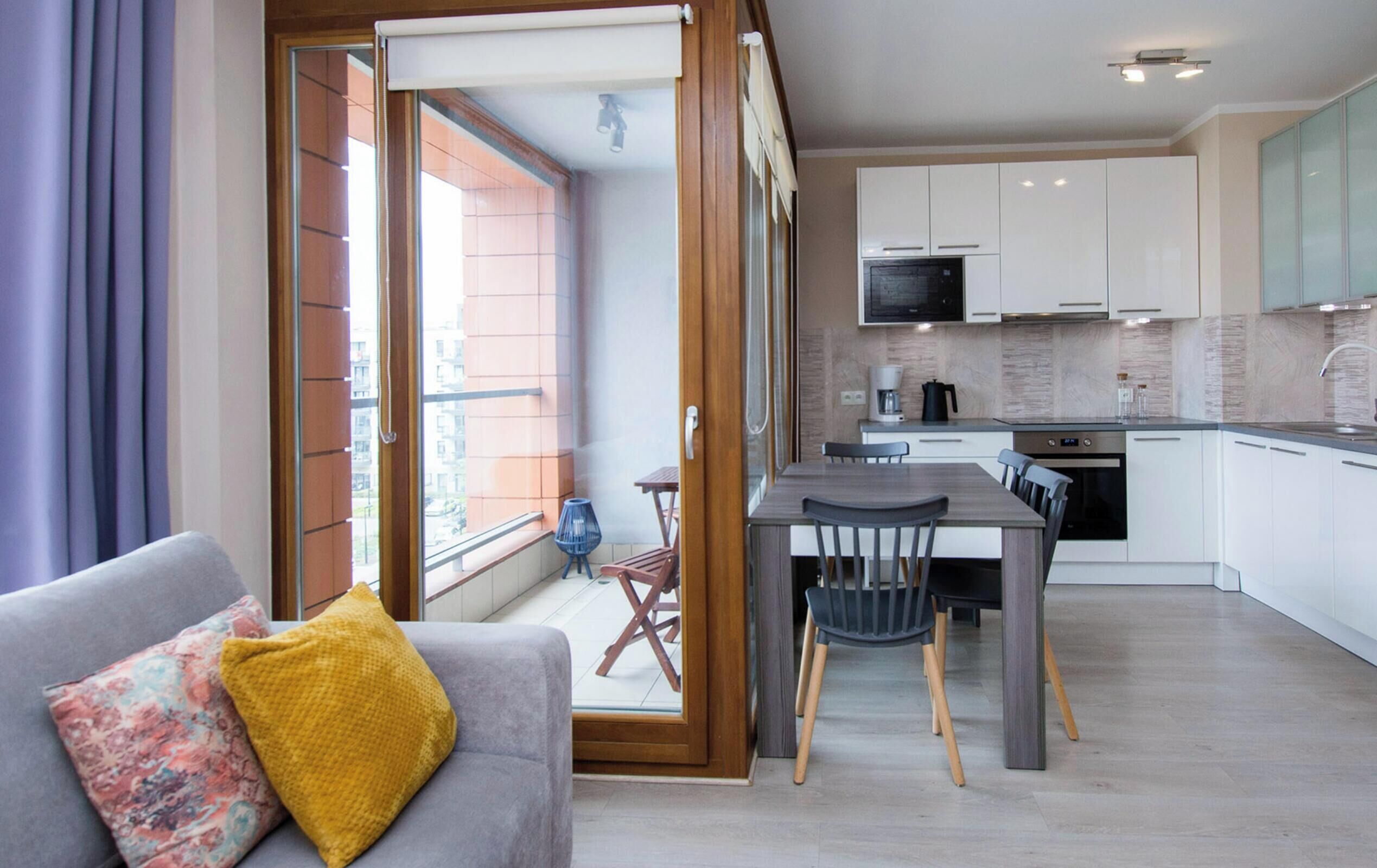 Un apartamento moderno con comedor, cocina y puerta corrediza de vidrio que da a un balcón.
