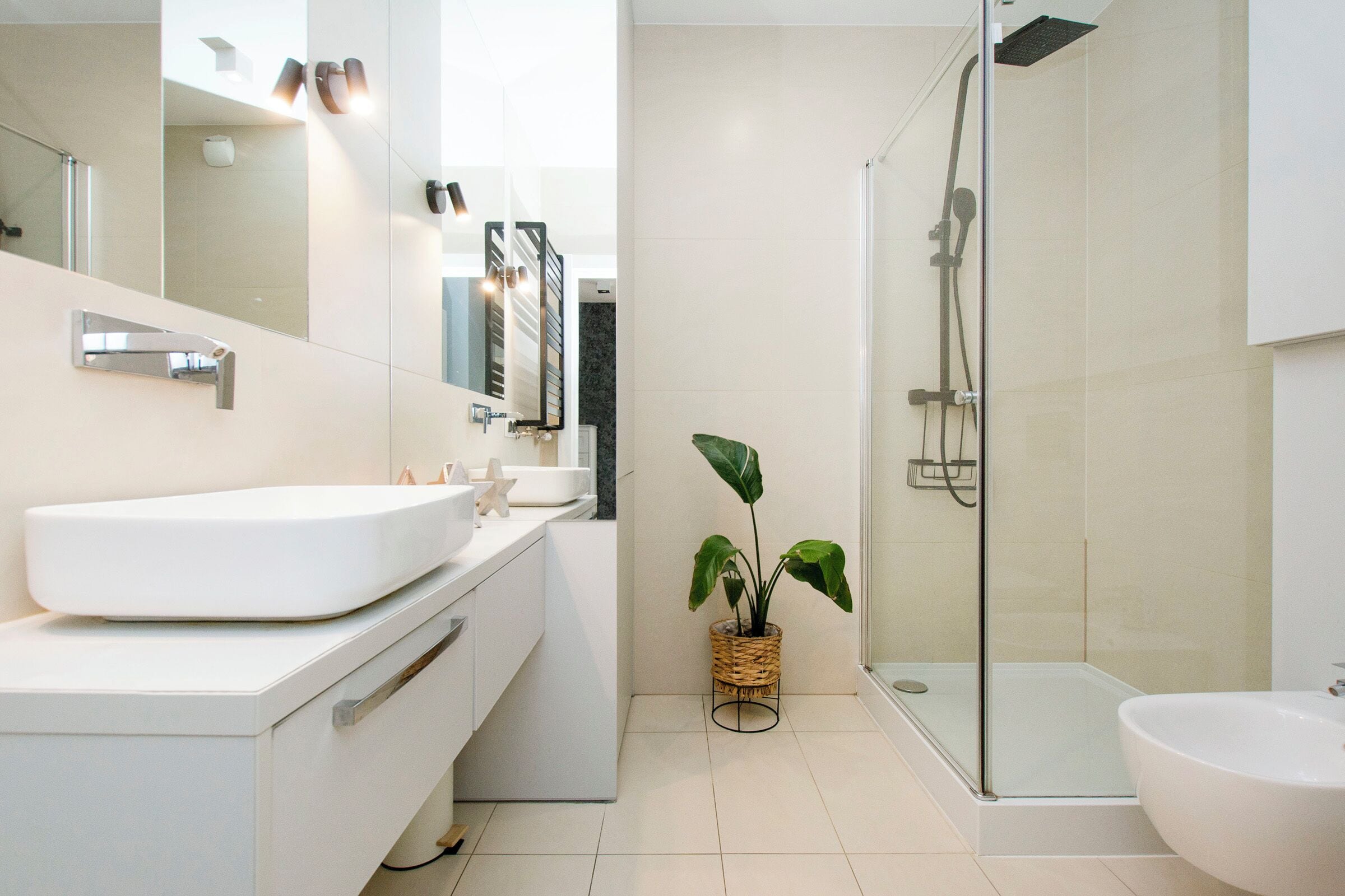 A modern bathroom with a large mirror, white sink, and a glass shower enclosure.