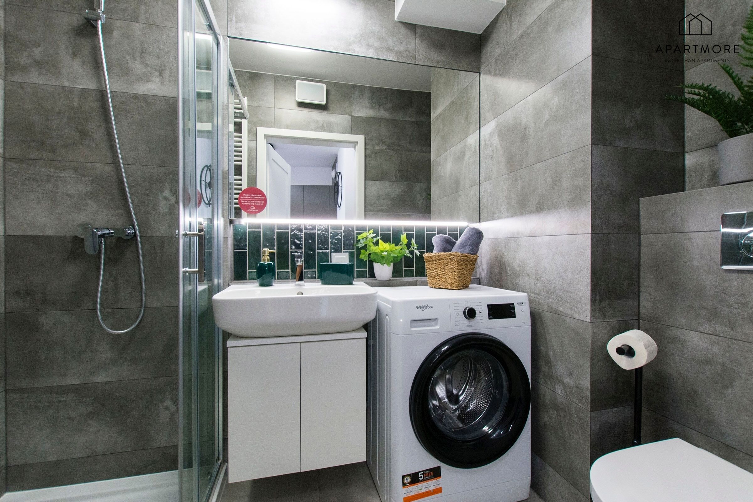 Ein modernes Badezimmer mit einer Duschkabine, einem integrierten Waschbecken, einer Waschmaschine und einer Toilette.