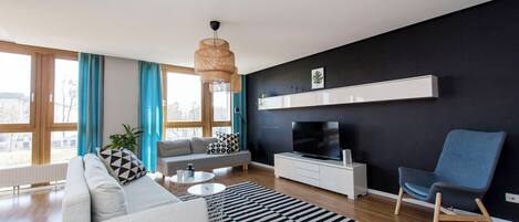 Una sala de estar moderna con un sofá, un televisor, un sillón, una mesa de centro y un tapete a rayas.