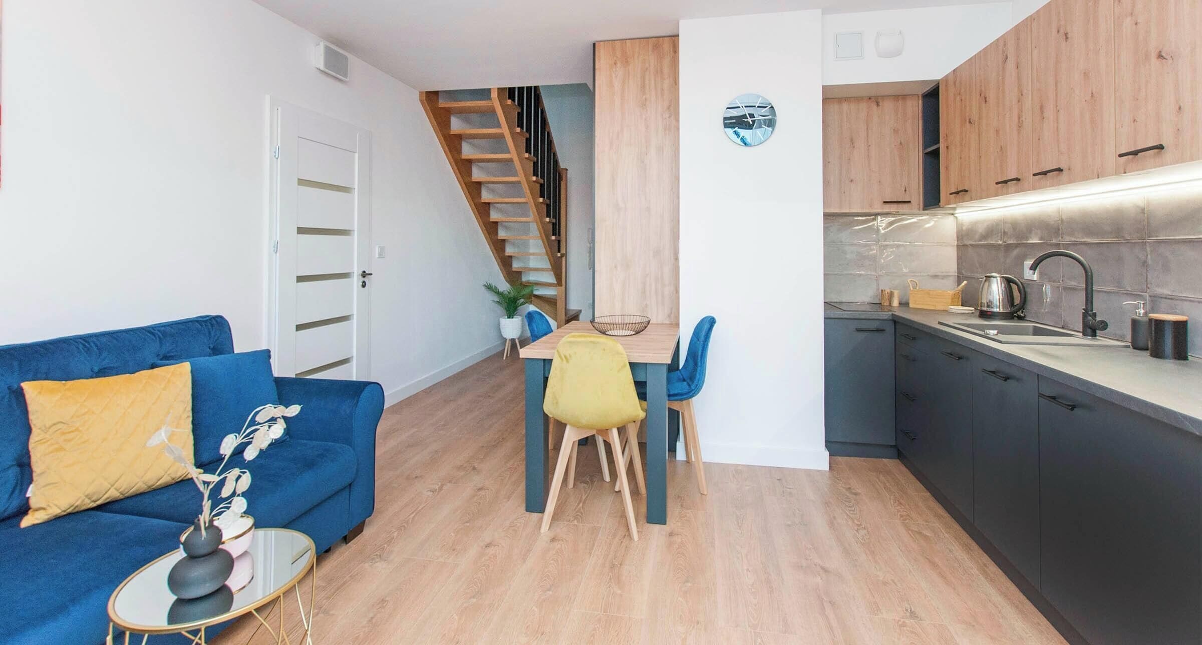 A compact living space with a dining area, kitchen, and a staircase.