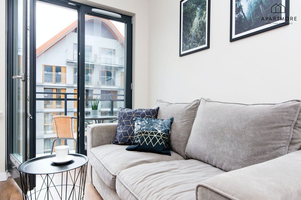 Ein modernes Wohnzimmer mit einer Couch, einem runden Tisch und einem Sessel. An der Wand hängen zwei gerahmte Bilder.