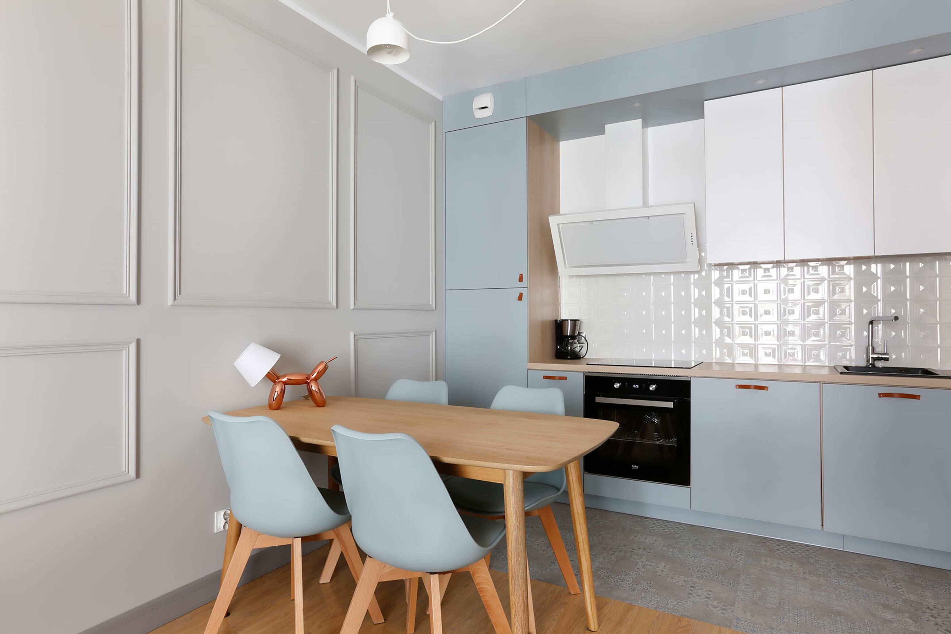 Una cocina moderna con una mesa y sillas de madera, una cafetera y un horno empotrado.