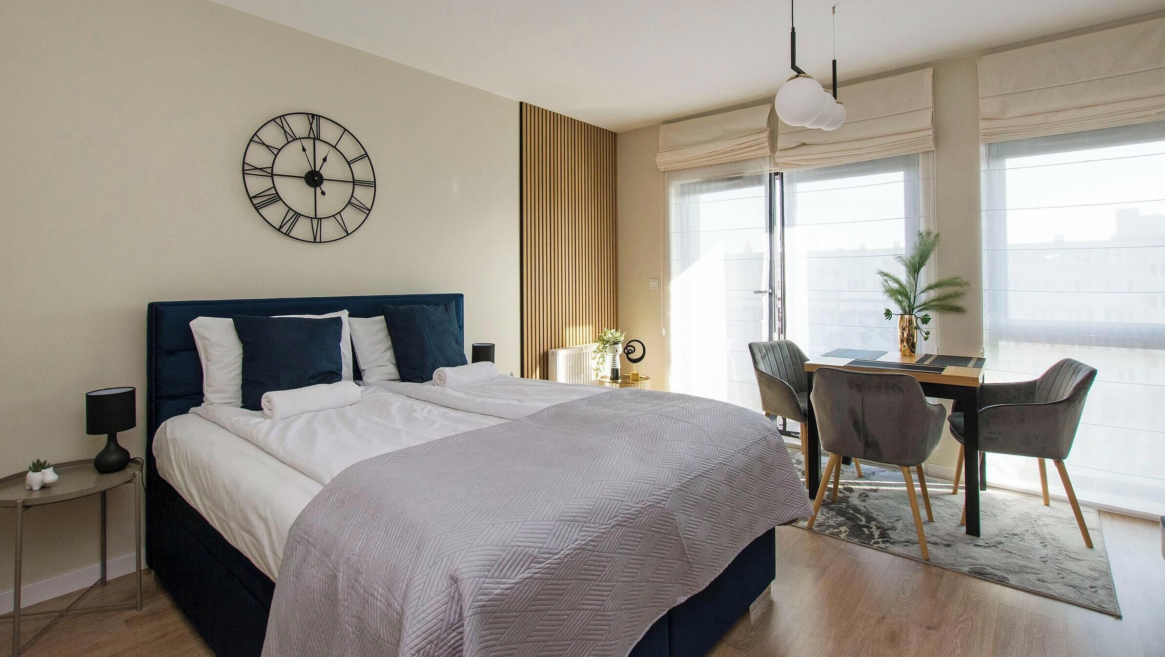 A modern hotel room with a large bed, a desk, and a view of the city.