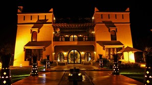Una imponente entrada de hotel con un arco central, fachada simétrica y un camino bien iluminado hacia la entrada.
