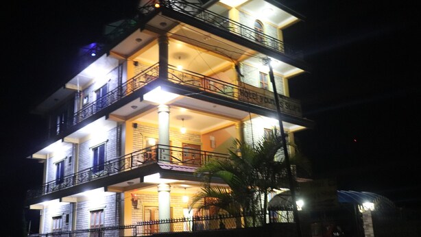 A multi-story hotel with balconies and a well-lit facade. - Hotel Young's Stupa (Lekhnath)