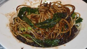A plate of noodles with greens on a checkered tablecloth. - Hotel Young's Stupa (Lekhnath)