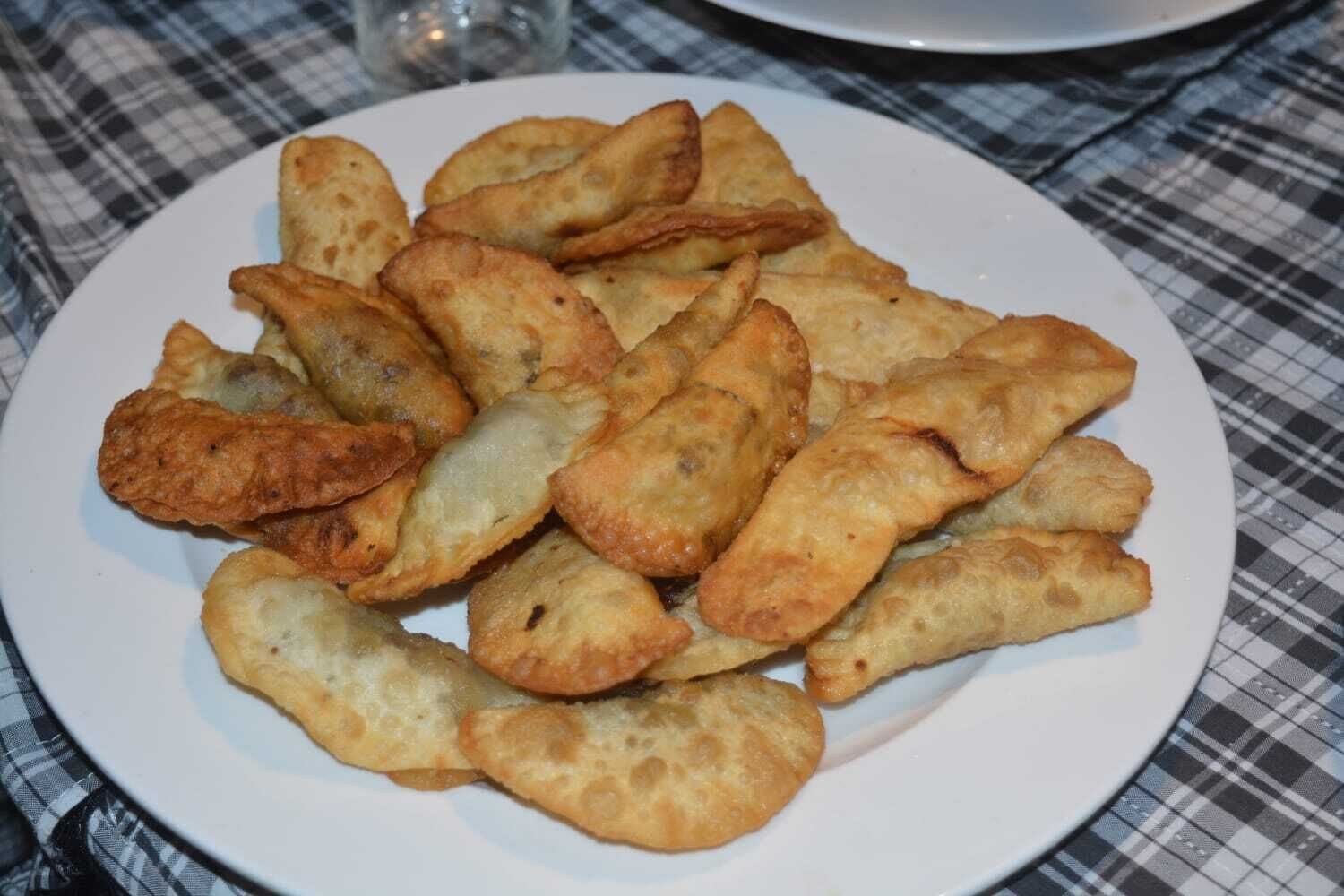 Une assiette de pâtisseries frites posée sur une nappe à carreaux.