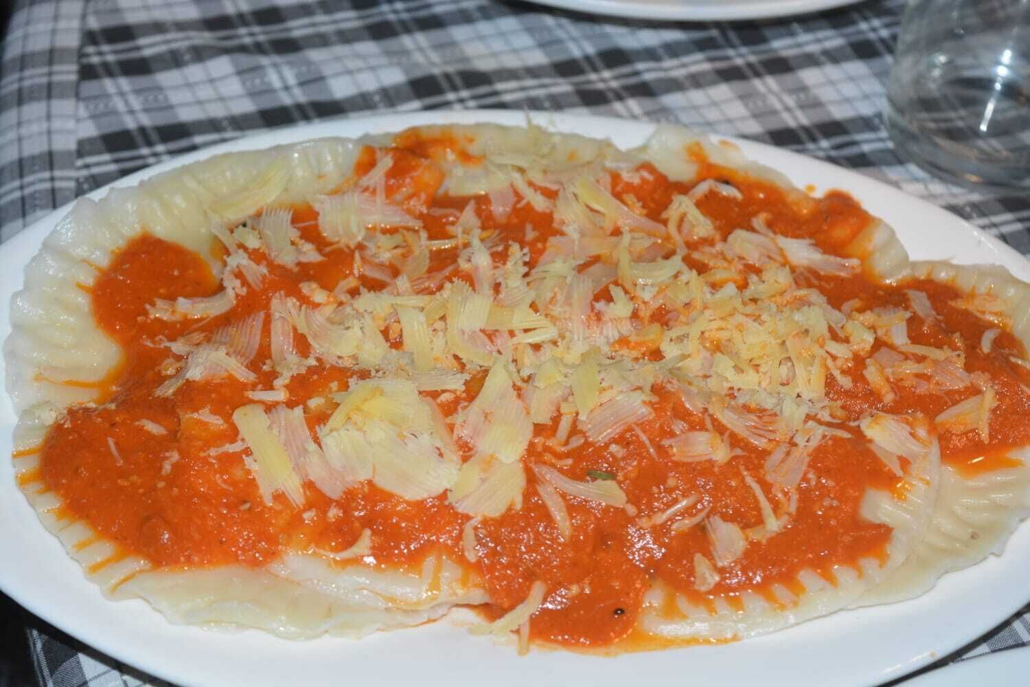 Um prato de comida com molho de tomate e repolho ralado sobre uma toalha xadrez.