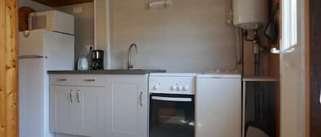 A compact kitchen with white cabinets, a built-in oven, a coffee maker, and a microwave.