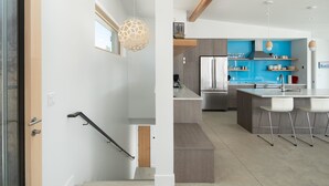 Een moderne keuken met een centraal eiland, roestvrijstalen apparatuur en barstoelen.