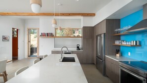 Een moderne keuken met een centraal eiland, ingebouwde apparatuur en een blauwe accentmuur.