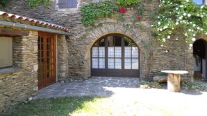 Un edificio de piedra con una entrada arqueada, una puerta de madera y una pequeña mesa al frente.
