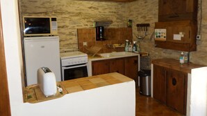 Una cocina compacta equipada con refrigerador, estufa, microondas y pileta.