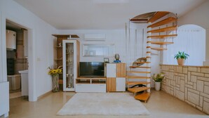 Un soggiorno moderno con una scala a chiocciola, un televisore e una libreria.