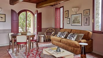 Una sala acogedora con un sofá marrón, ventanas con marco rojo y un tapete de estampado rojo.