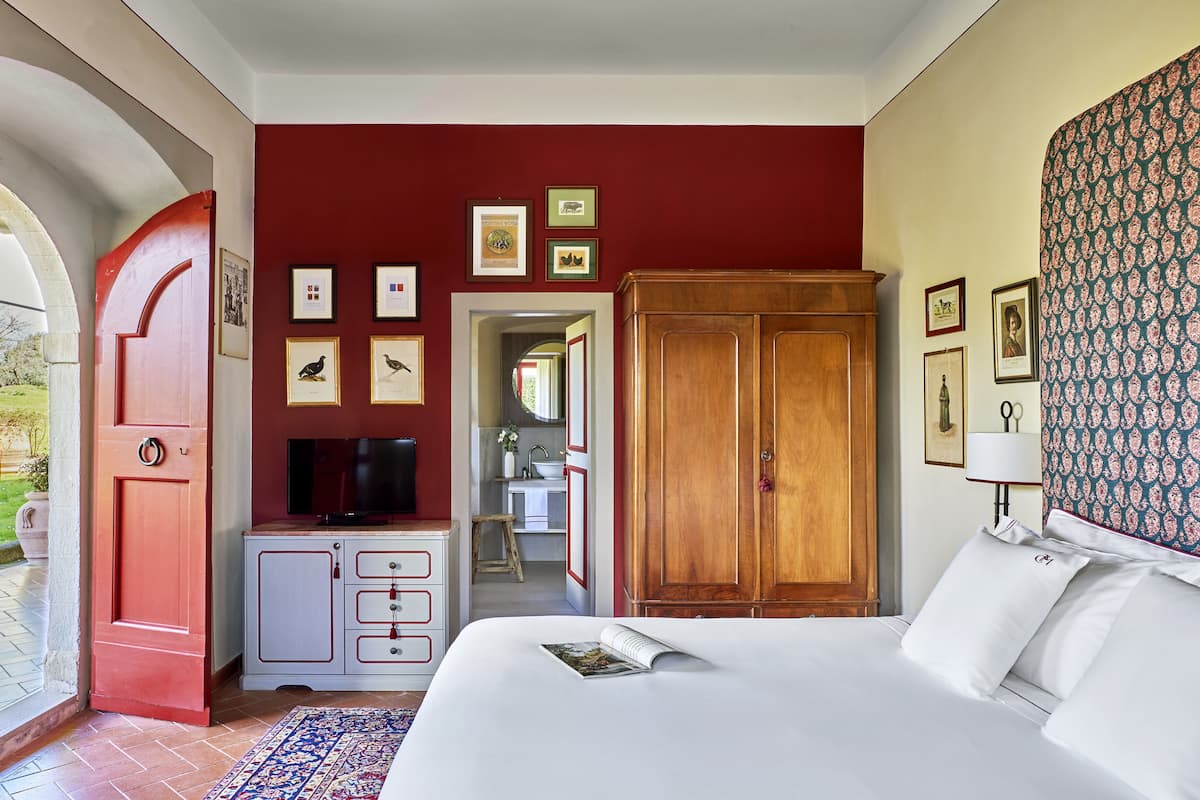 Une chambre d’hôtel avec un lit, une télévision, une armoire et une salle de bain visible à travers une porte ouverte.