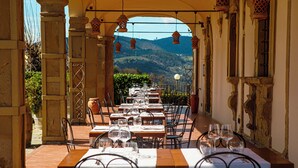 Un espace de restauration en plein air, avec des tables disposées pour deux personnes, offrant une vue sur un paysage montagneux.