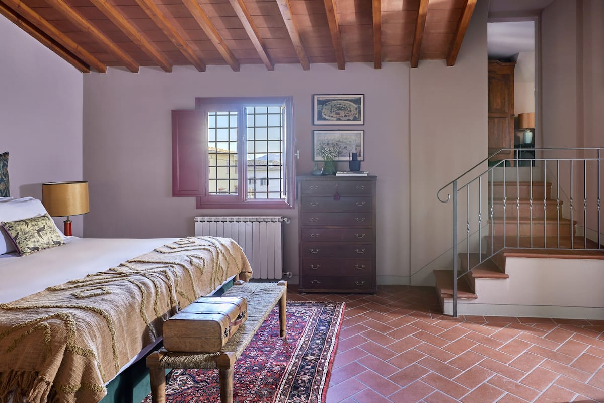 Une chambre à coucher comprenant un lit, un banc, une commode et un escalier.