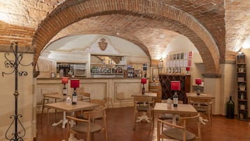A restaurant with brick arches, wooden tables, and chairs, a bar area with bottles, and a wine rack.