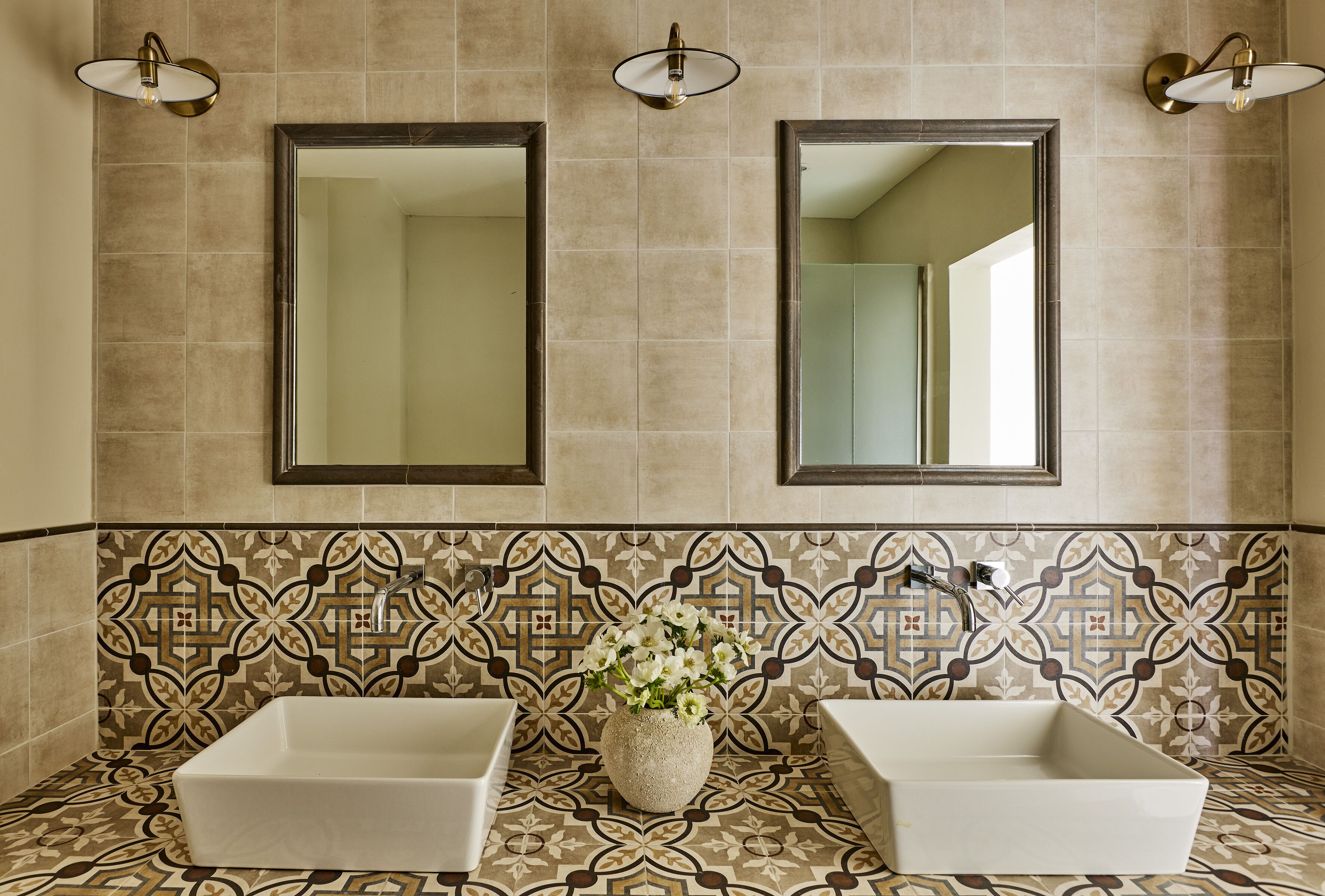 Un bagno con due lavandini, uno specchio e piastrelle decorate.