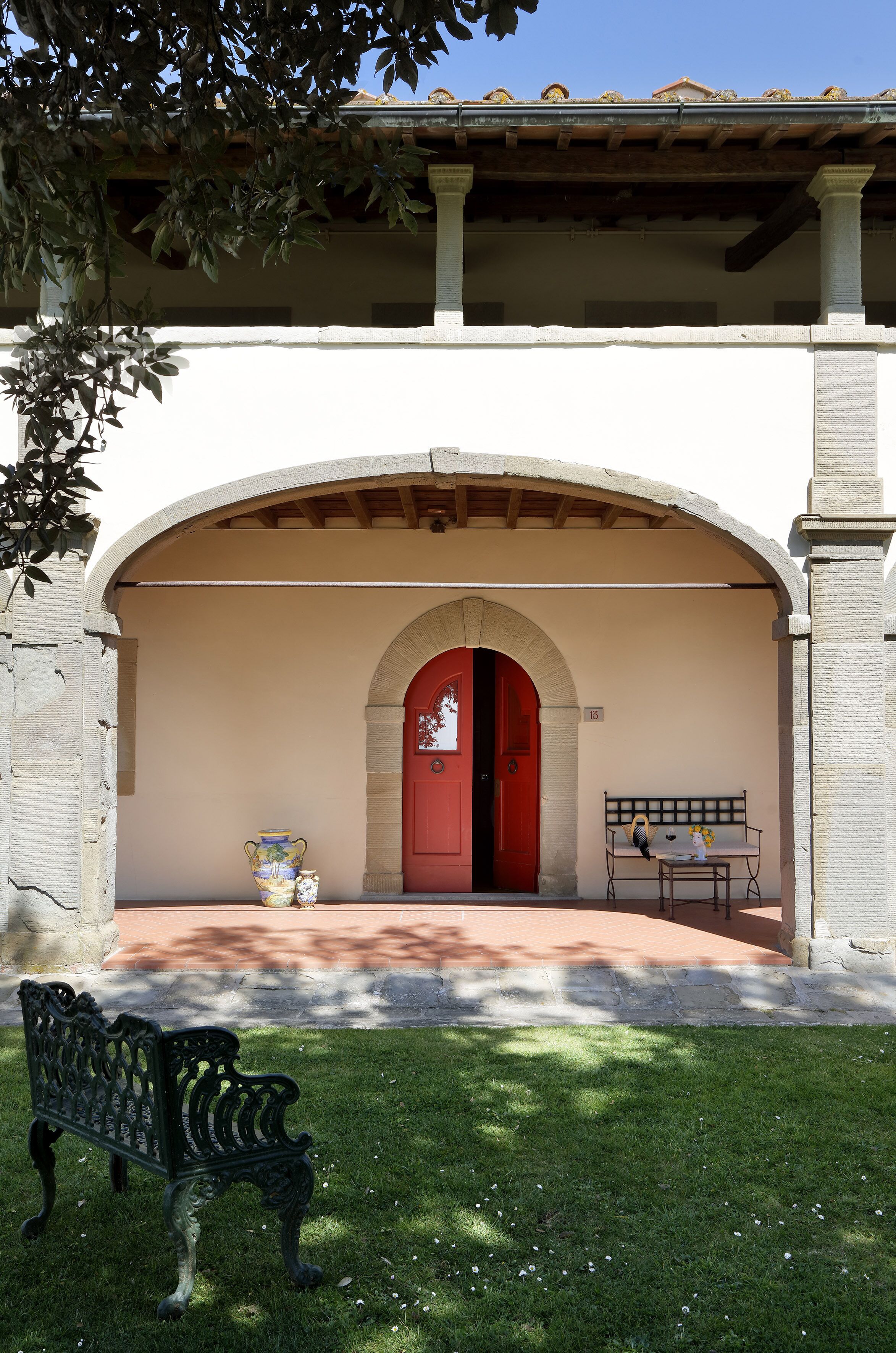 L'ingresso di un edificio con una porta rossa, una panchina e un vaso sui gradini.