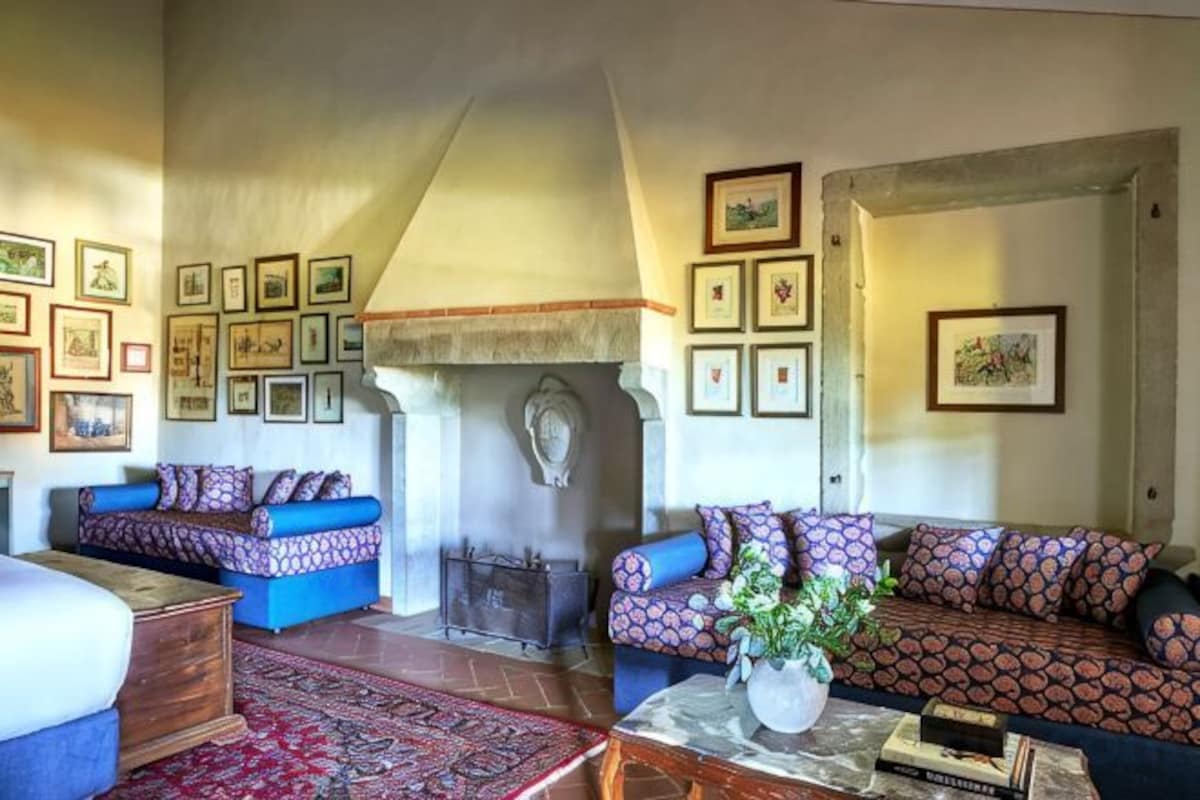 Una sala de estar con dos sofás, una chimenea y cuadros en las paredes.