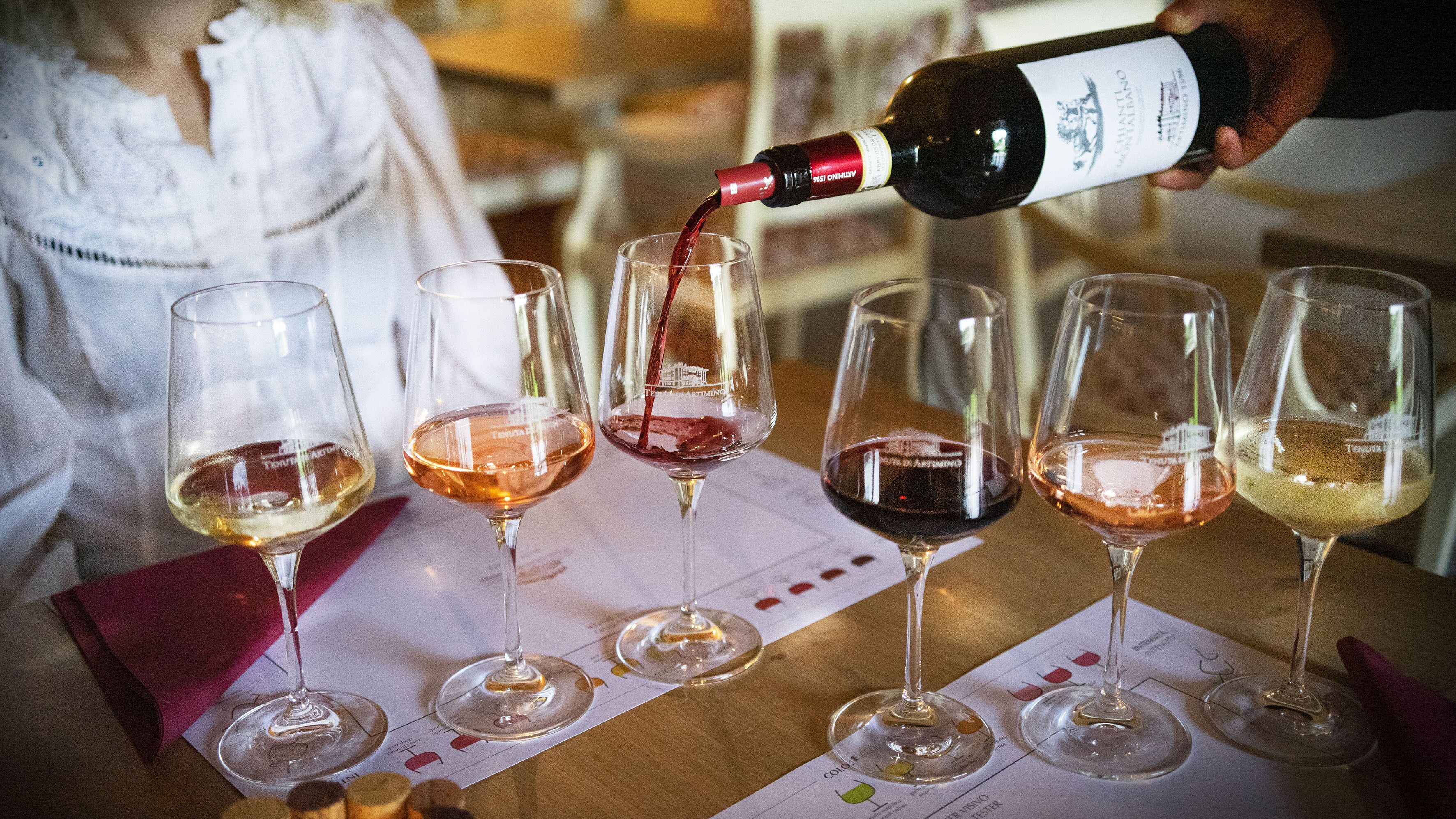 Un evento de degustación de vinos con varias copas sobre una mesa, cada una con un color diferente de vino.
