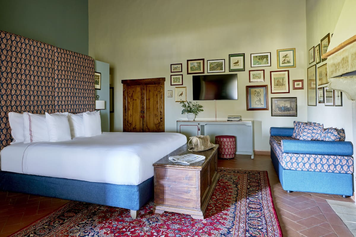 Une chambre à coucher avec un grand lit, une commode en bois, un téléviseur et un canapé bleu.