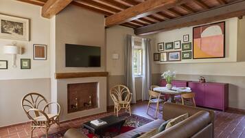 A living room with a fireplace, a television, and a dining area with a pink cabinet.
