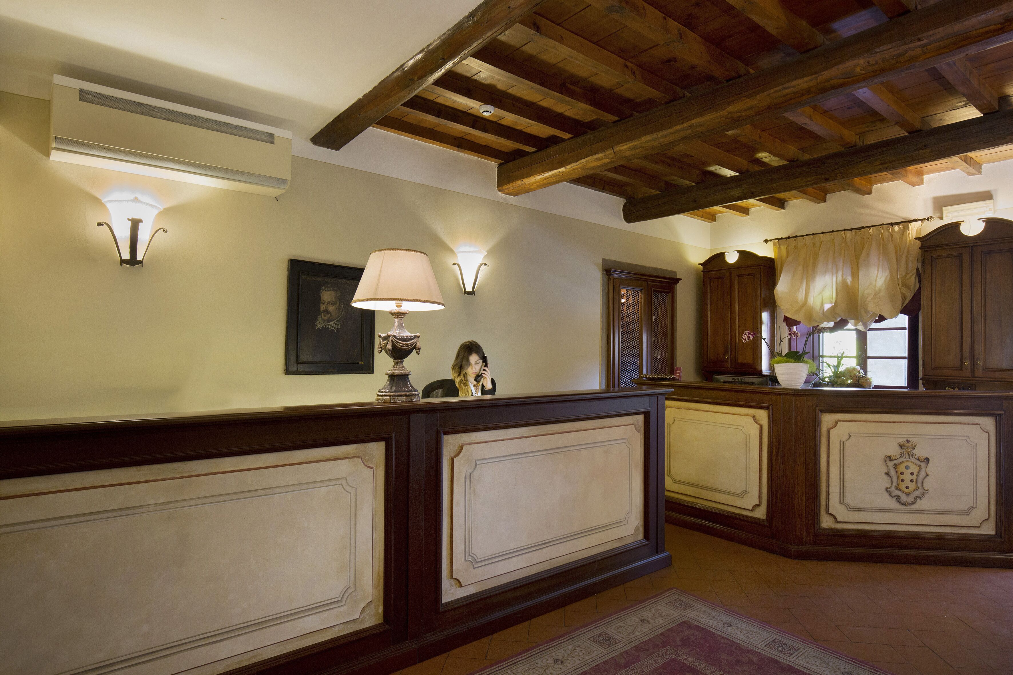 A reception area with a wooden reception desk, wall-mounted lamps, and a framed portrait.