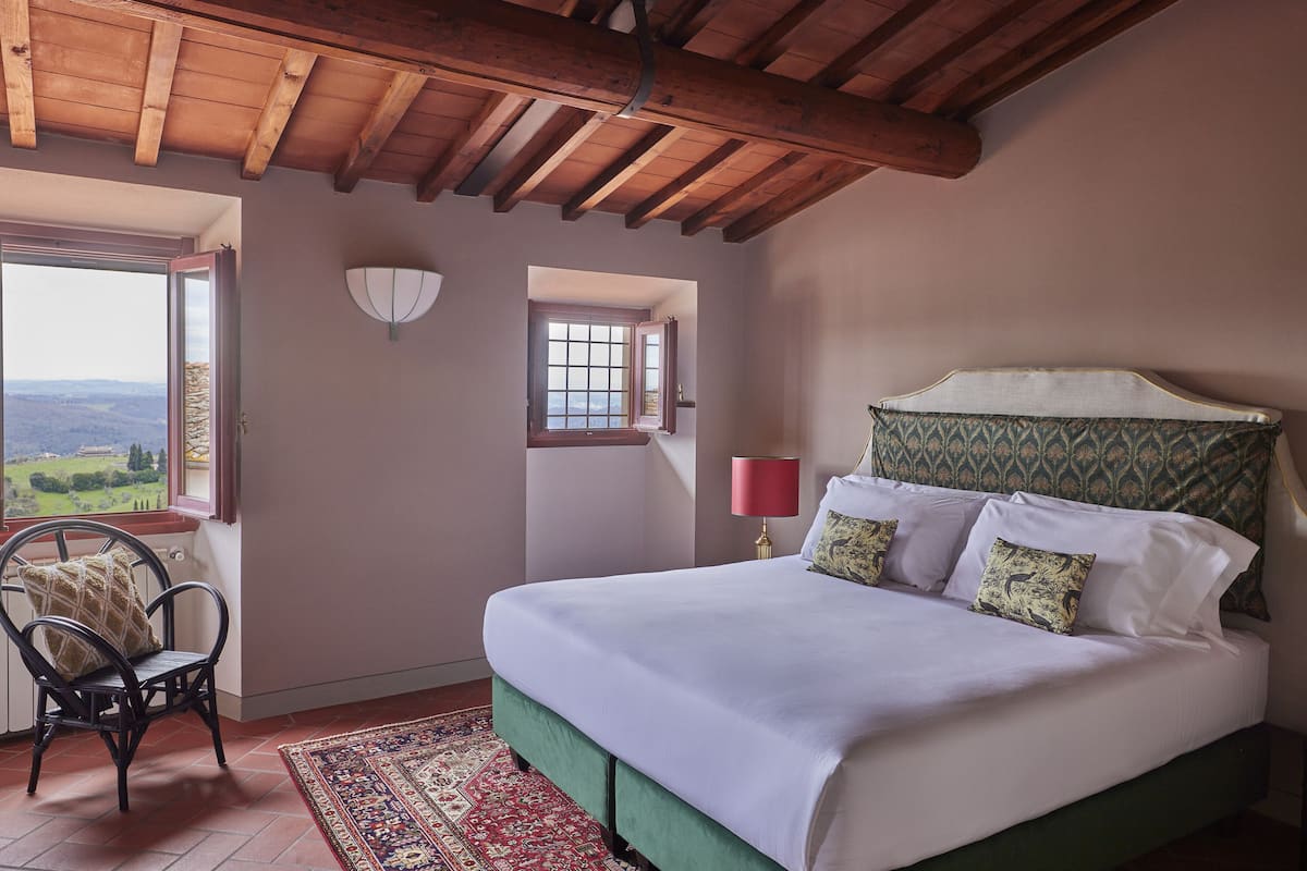 Une chambre à coucher avec un lit, une chaise, une fenêtre et une vue sur l’extérieur.