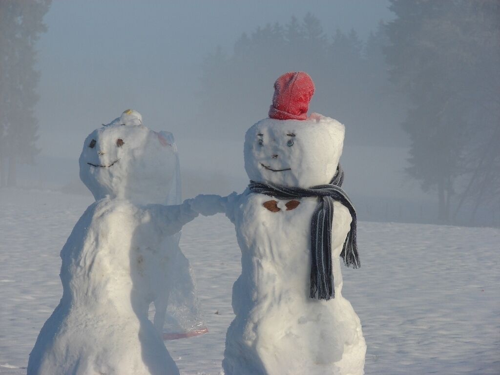 Zwei Schneemänner in einer verschneiten Landschaft.