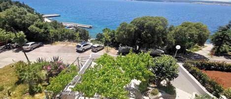 Vista costera con coches aparcados, un muelle y un aparcamiento.