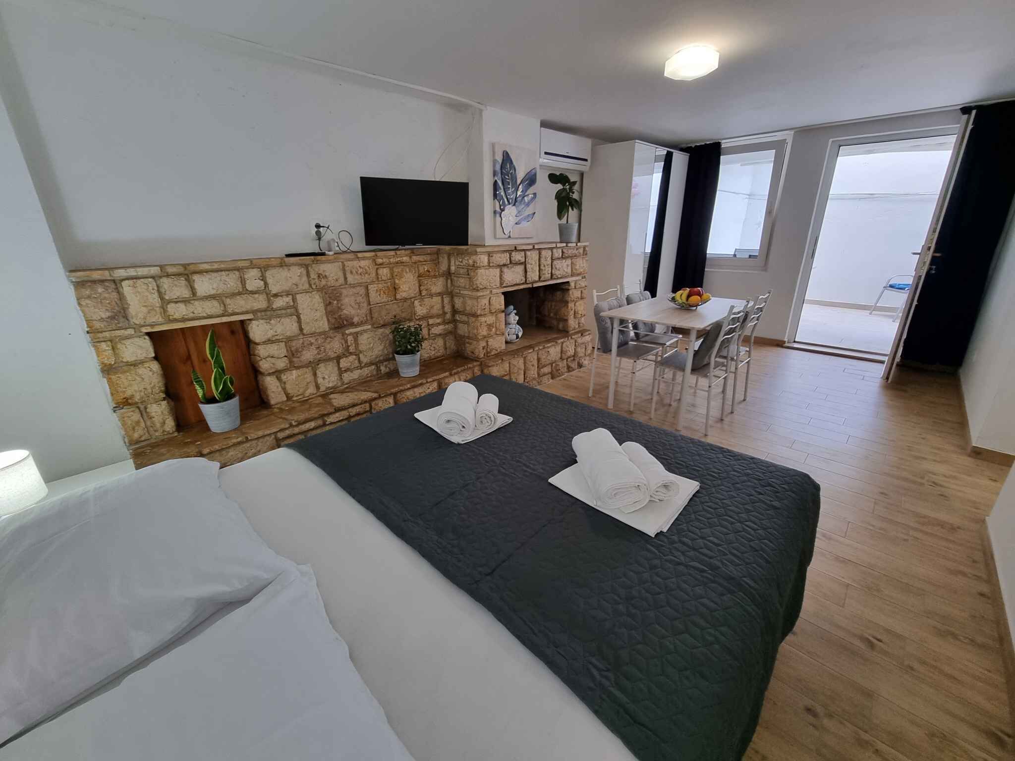 A hotel room with a stone fireplace, a flat-screen TV, a dining area with a table and chairs, and a balcony with a view.