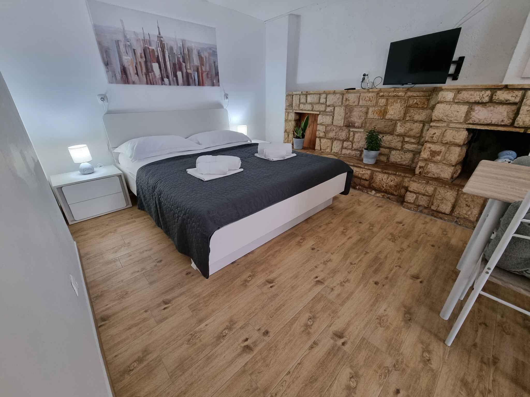 Ein Schlafzimmer mit Bett, Nachttisch, Fernseher, Kamin aus Stein und einem Bild an der Wand.