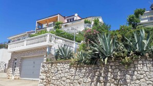 Un immeuble résidentiel avec un mur en pierre, un garage et un balcon doté d’une balustrade.