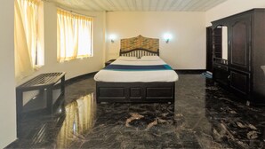 A bedroom with a bed, a wooden wardrobe, a bench, and a window with curtains. - Pavithram Homestay (Devikolam)