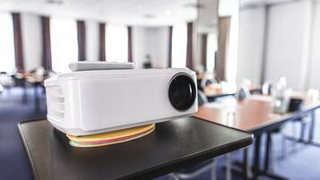 A projector on a table in a room with a modern design, featuring a long table and chairs.