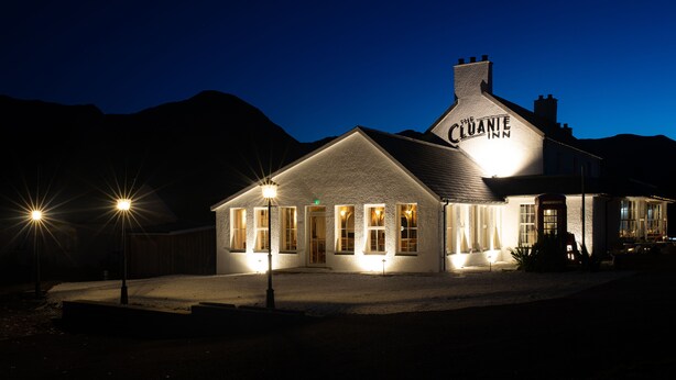 A building with the name "Cuanie" illuminated at night, featuring a prominent chimney, multiple windows, and a well-lit entrance. -  The Cluanie Inn (Inverness)