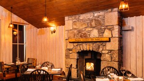 A cozy restaurant with stone walls, a fireplace, wooden tables, and chairs. -  The Cluanie Inn (Inverness)