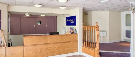 A reception desk with a wooden finish, a sign for Redwings Lodge, and a staircase with a wooden railing.