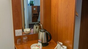 A compact bathroom with a wooden vanity, a mirror, a kettle, a bowl, and a cup. - Redwings Lodge Solihull (Solihull)