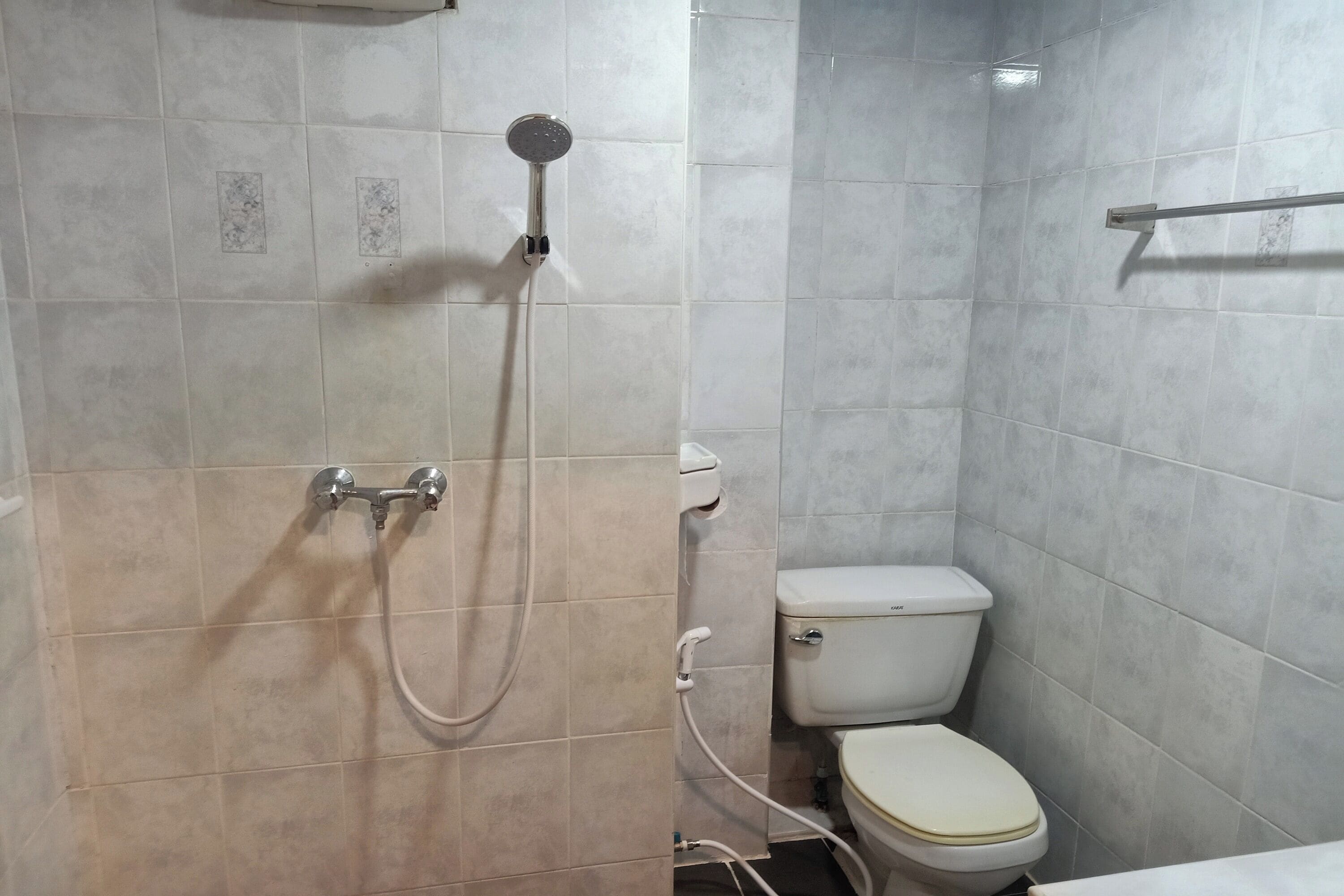 A bathroom with a shower, toilet, and tiled walls.