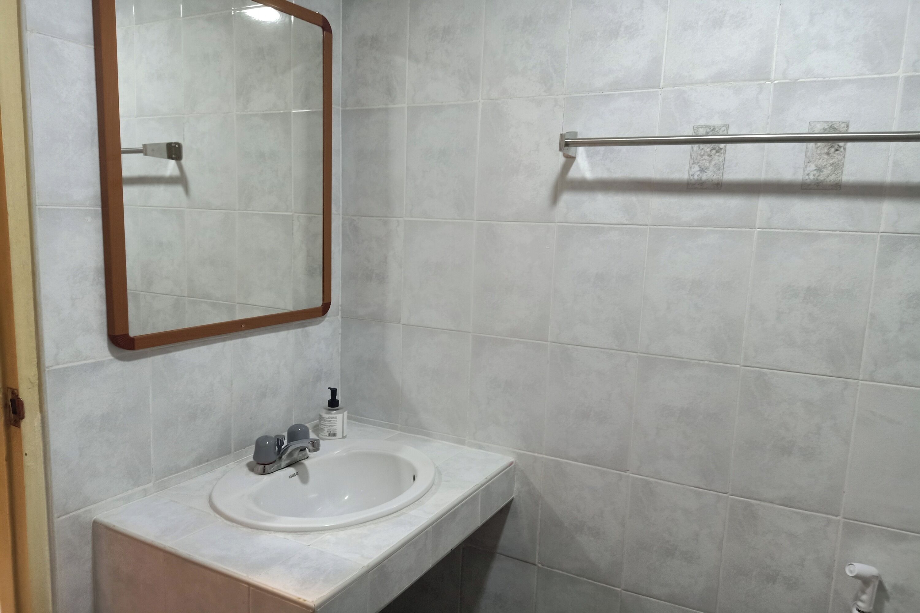 Une salle de bain avec un lavabo blanc, un miroir et des murs carrelés.