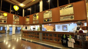 Un vestíbulo amplio con mostrador de recepción, ventanas grandes y elementos decorativos como faroles y arte mural.