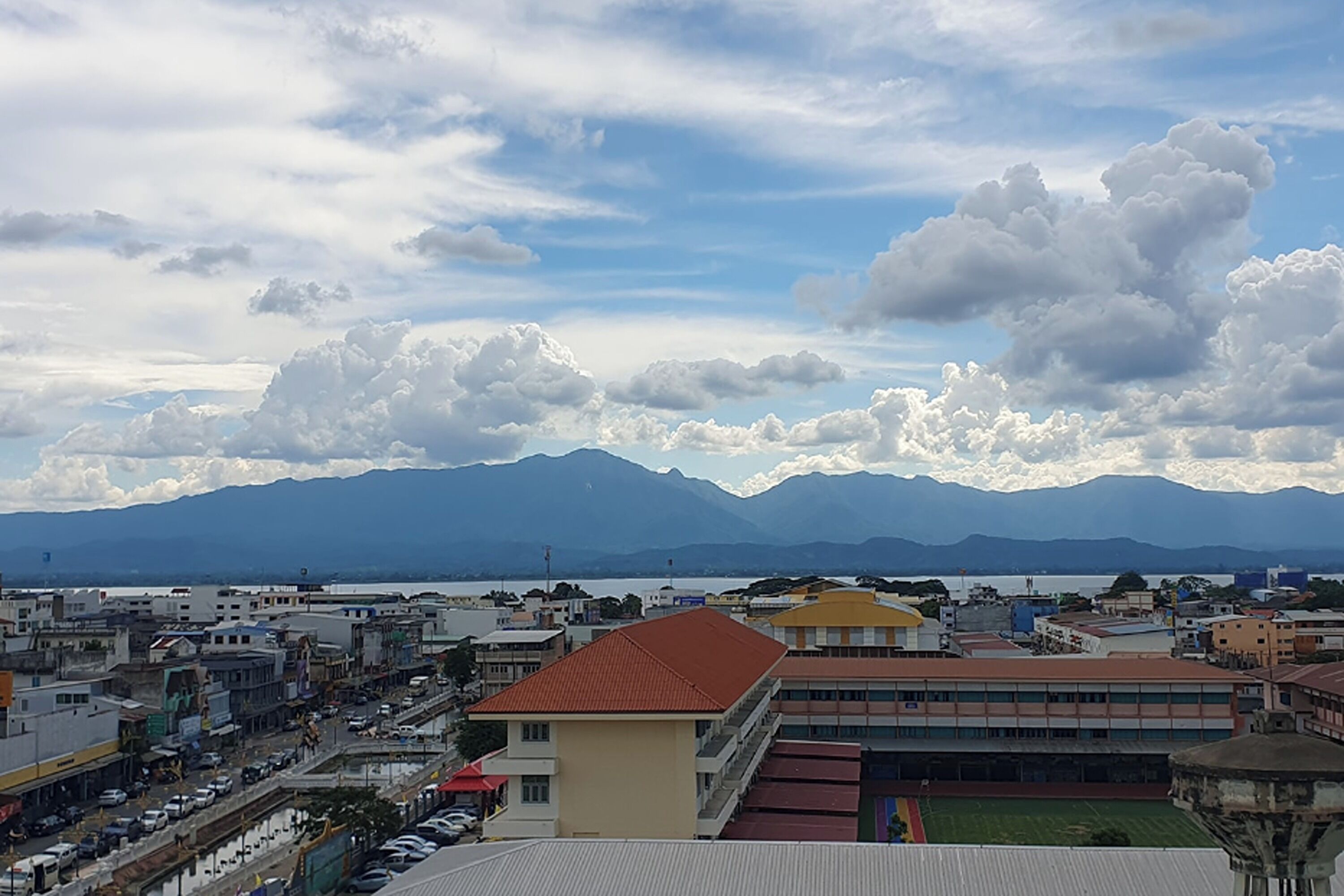 Un paisaje urbano con un edificio destacado, techo rojo y un amplio espacio abierto al frente.