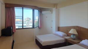 Habitación de hotel con dos camas, televisión, lámpara y ventana con cortinas.