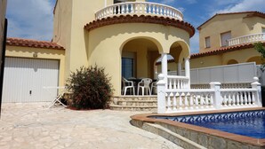 A two-story building with a pool, outdoor seating, and a white fence. - Villa with private pool for 7 people, 4000m from the beach, private pool (L'Ametlla de Mar)
