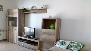 A living room with a TV on a wooden stand, a sofa with patterned cushions, and a wooden cabinet with drawers and shelves. - Villa with private pool for 7 people, 4000m from the beach, private pool (L'Ametlla de Mar)
